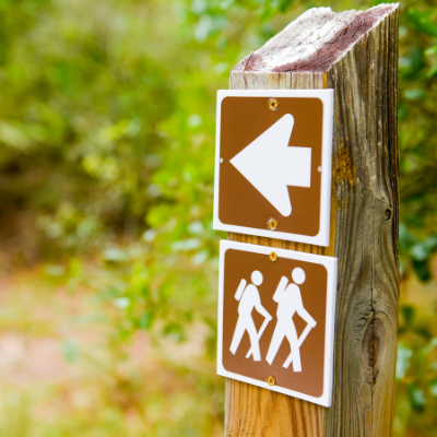 wood post in woods showing arrow for directions for hikers